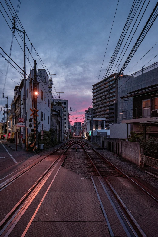 a train traveling down train tracks next to tall buildings, unsplash, sōsaku hanga, 8k hdr sunset lit, abandoned streets, 2022 photograph, full frame image