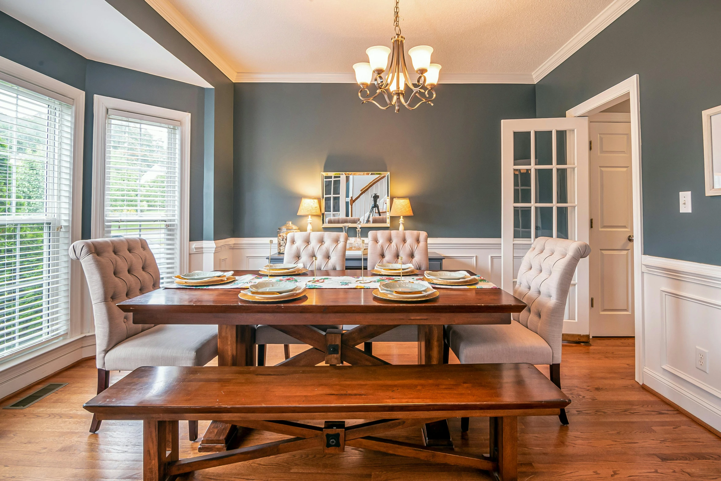 an elegant dining area with wood flooring and fancy chandelier