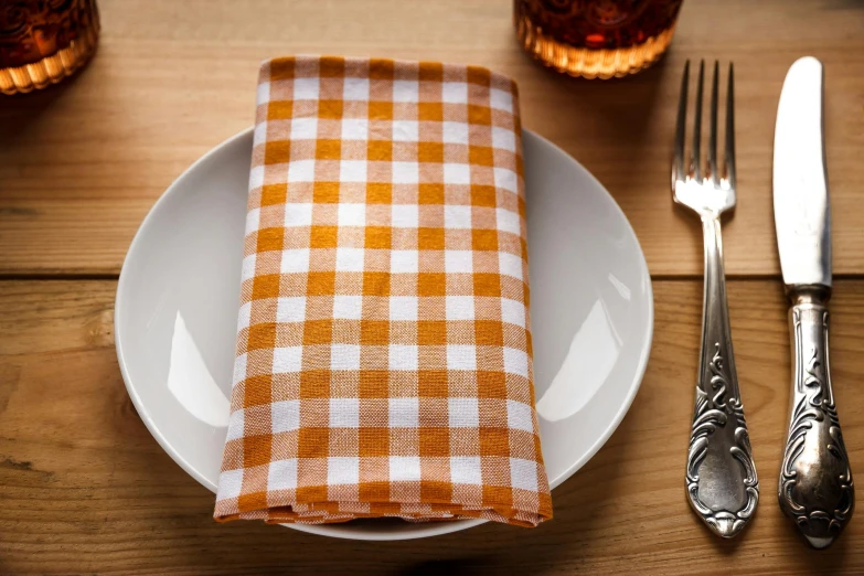 a white plate topped with a checkered napkin, by Daniel Gelon, unsplash, orange, square, brown, scottish