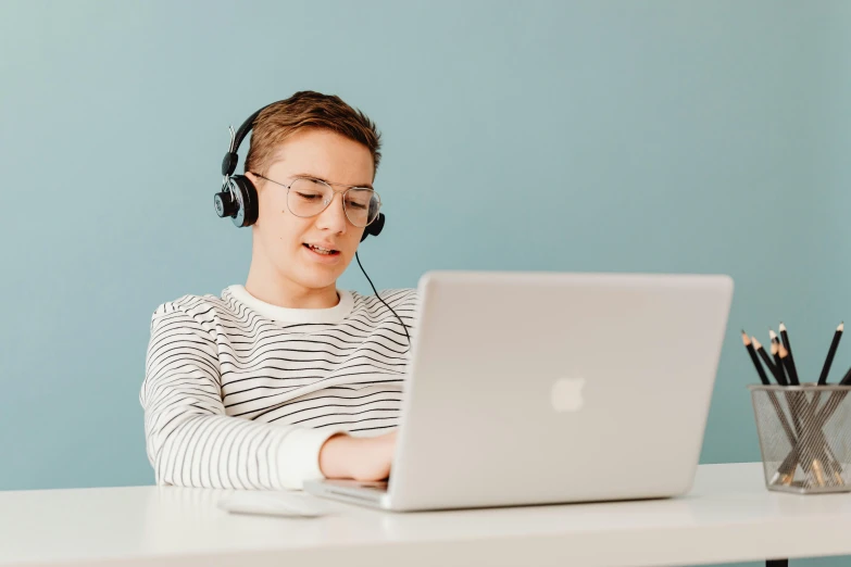 a person sitting at a table with a laptop and headphones, trending on pexels, teenage boy, avatar image, professional image, lachlan bailey