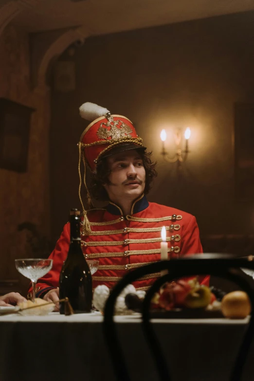 a man wearing an officer's outfit is sitting at a table with wine