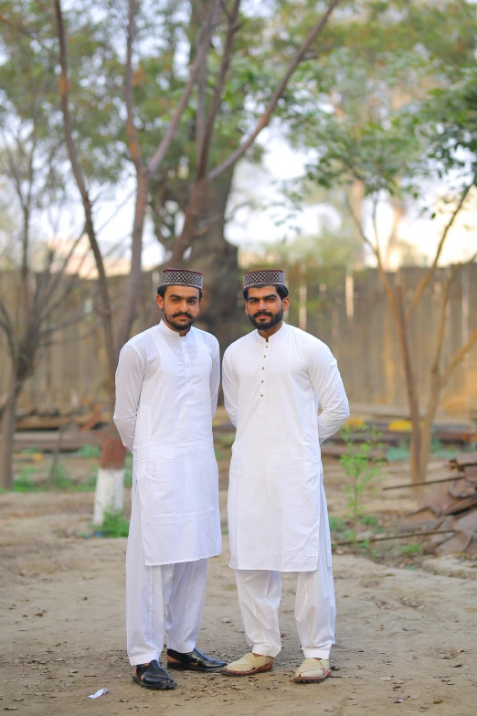 two men are standing together outside in white