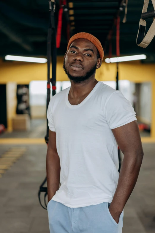 a man wearing a orange hat and white shirt standing in a room