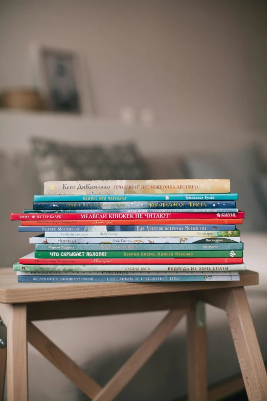 a stack of books sitting on top of a wooden table, children's artwork, placed in a living room, full product shot, multiple stories