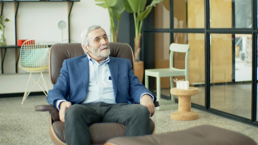 a man sitting in a chair in a room, gray beard, commercial, ahmad merheb, at the sitting couch