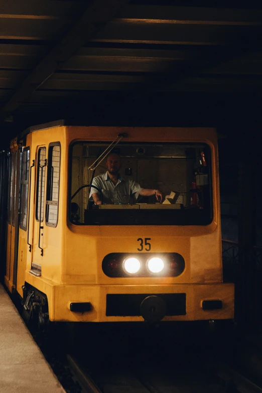 a yellow train pulling into a train station, a portrait, unsplash, in an underground laboratory, miners, matej ‘retro’ jan, brown