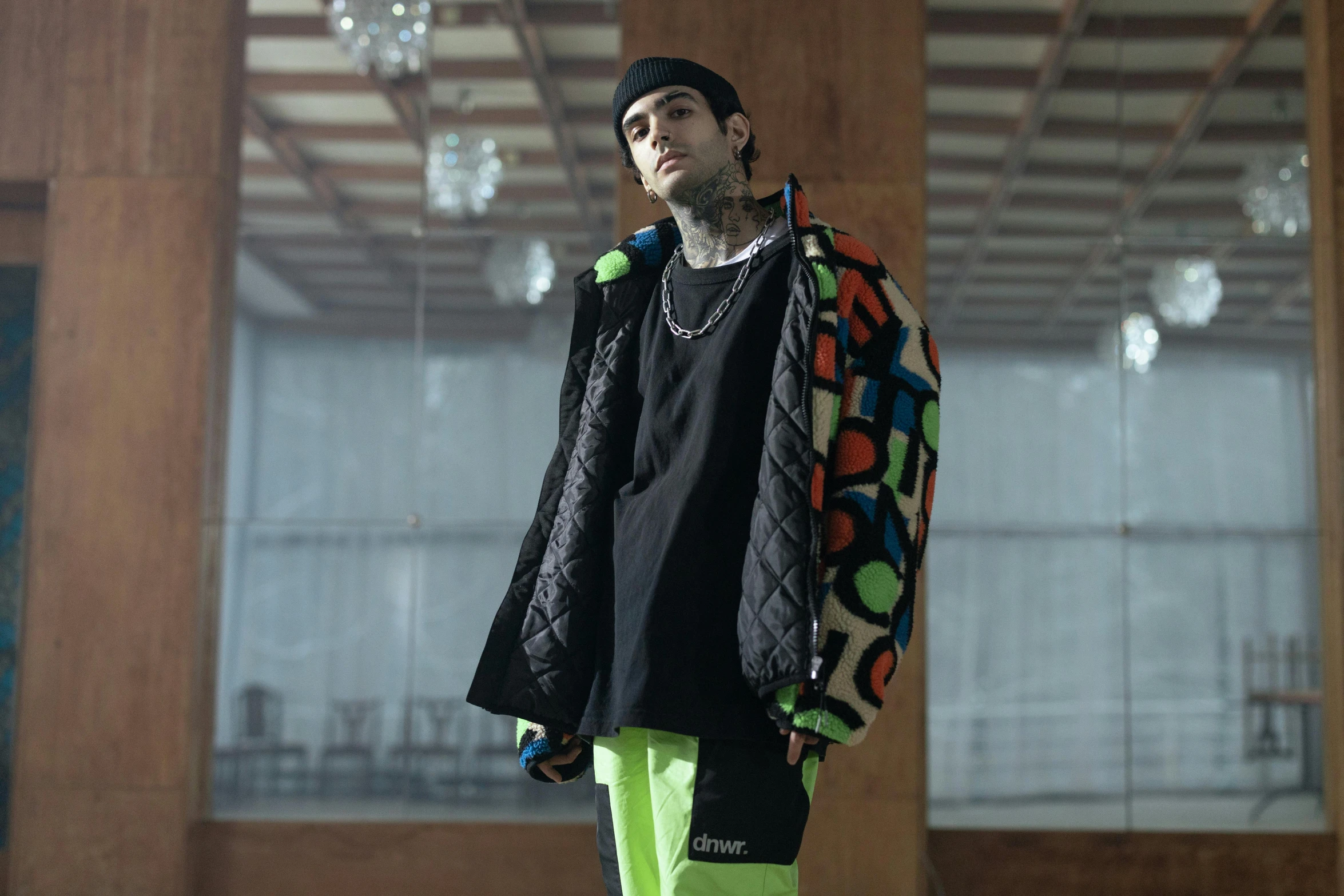 the man is standing in an art museum with a hat and green pants