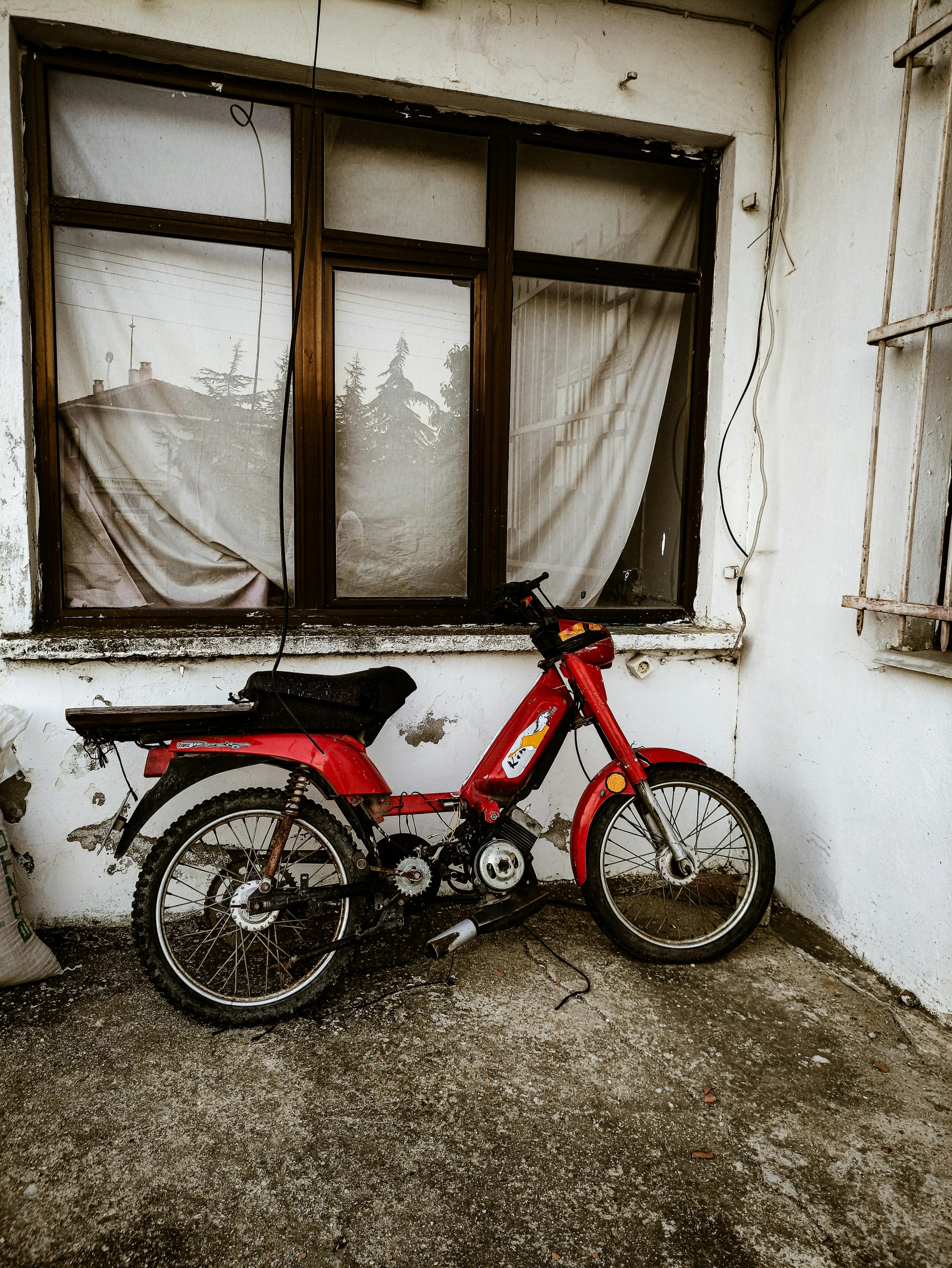 a red motorcycle parked in front of a window, by Kristian Zahrtmann, pexels contest winner, photo of poor condition, actual photo, 90's photo, moped