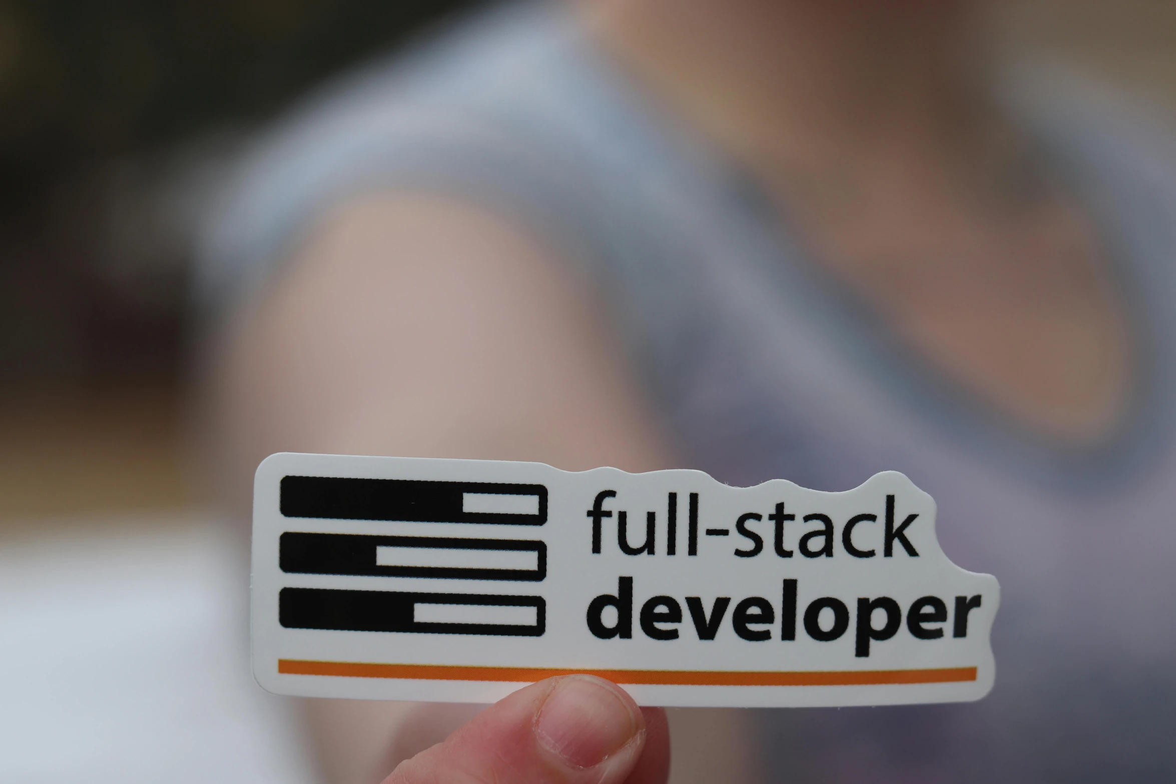 a person holding a sticker that says full stack developer, exterior shot, photorealistick, growing, ::