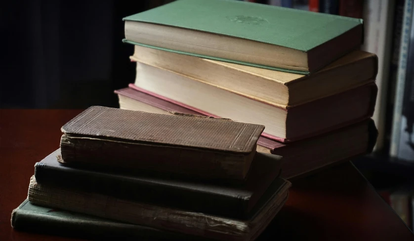 a stack of books sitting on top of a wooden table, by Alice Mason, pexels contest winner, australian tonalism, coloured photo, the library of babel, taken in the early 2020s, low-light