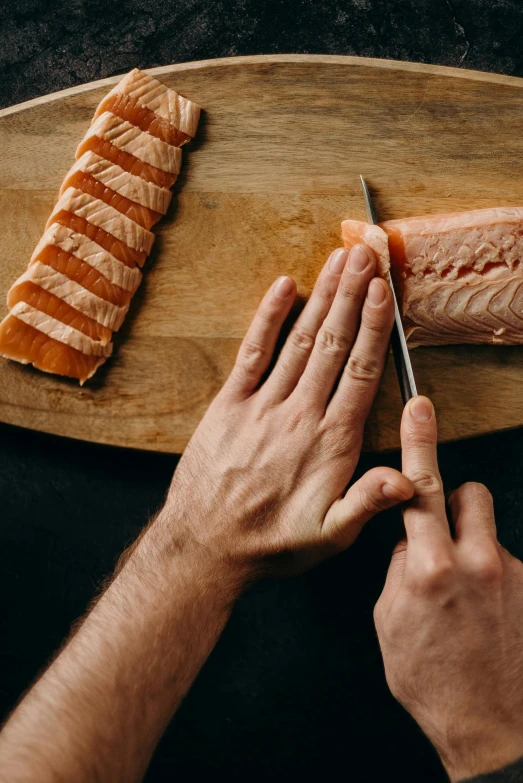 a person cutting a piece of salmon on a cutting board, by Daniel Seghers, extra fleshy hands, sculpting