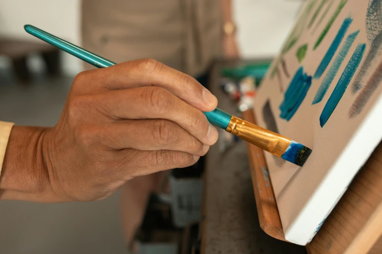 a close up of a person painting on a canvas, pexels contest winner, holding a paintbrush in his hand, prussian blue and raw sienna, digital artist, airbrush painting