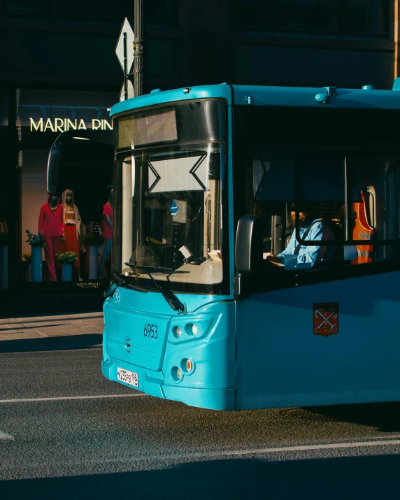 a blue bus driving down a street next to people