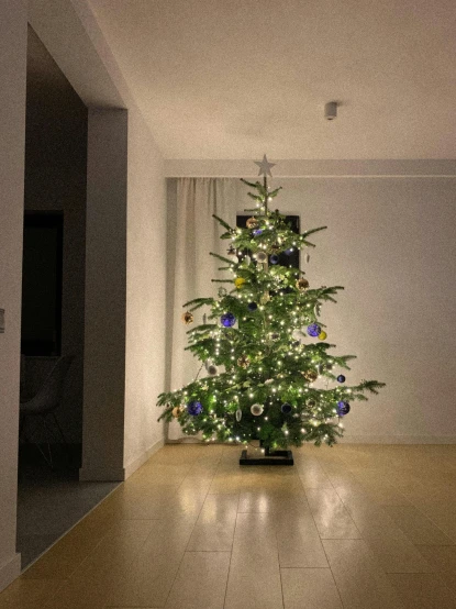 a lit christmas tree in the corner of a room