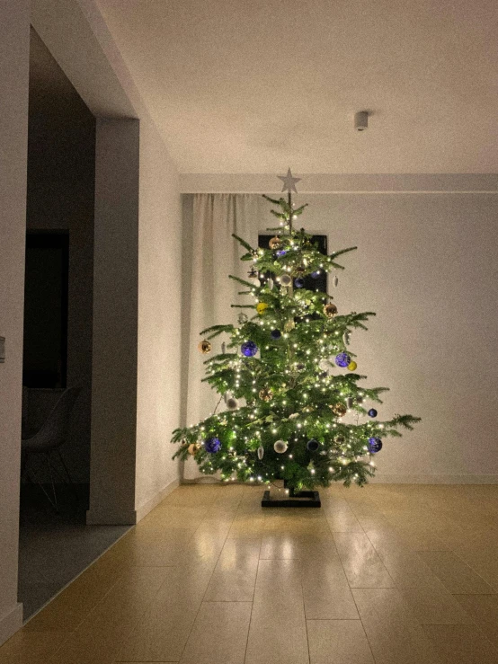 a lit christmas tree in the corner of a room