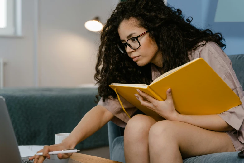 a woman sitting on a couch reading a book, a cartoon, trending on pexels, college students, lady using yellow dress, holding notebook, with glasses