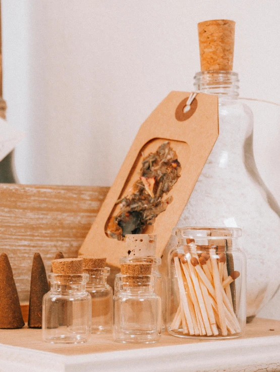 a table topped with bottles and wooden utensils, a picture, unsplash, incense, product label, close up portrait shot, profile image