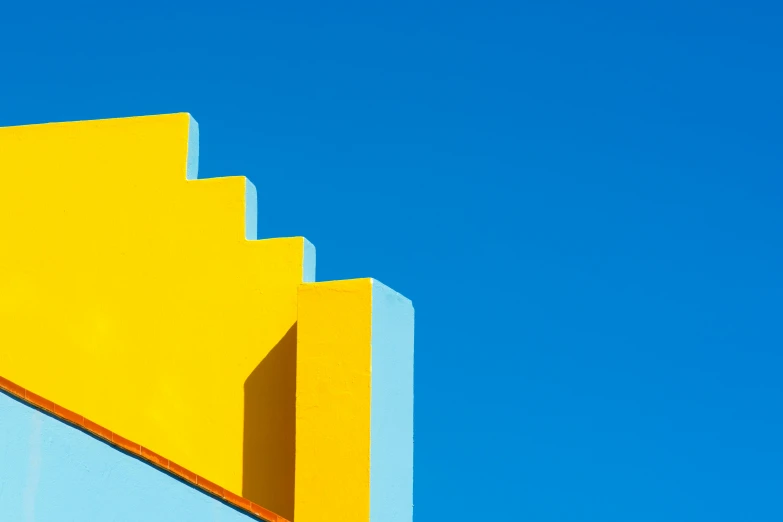 a yellow and blue building against a blue sky, inspired by Ricardo Bofill, unsplash contest winner, stylized neon, fins, minimalist photorealist, suns