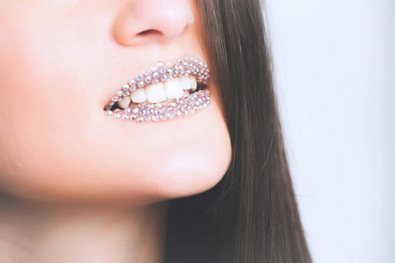 a close up of a woman with a smile on her face, a colorized photo, inspired by Hedi Xandt, trending on pexels, aestheticism, crystal teeth, sparkly, wide mouth, on grey background