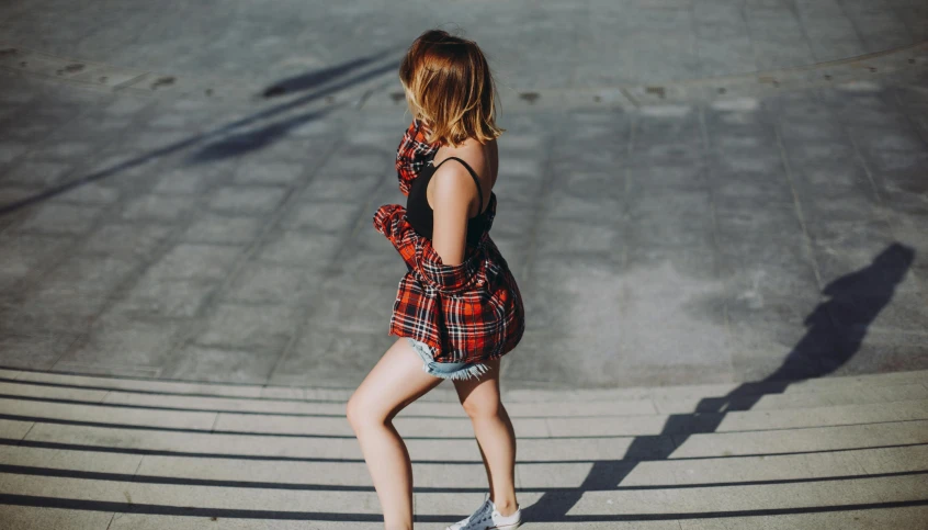 a woman riding a skateboard down a flight of stairs, pexels contest winner, happening, tartan garment, short minidress, walking away, doing a sassy pose