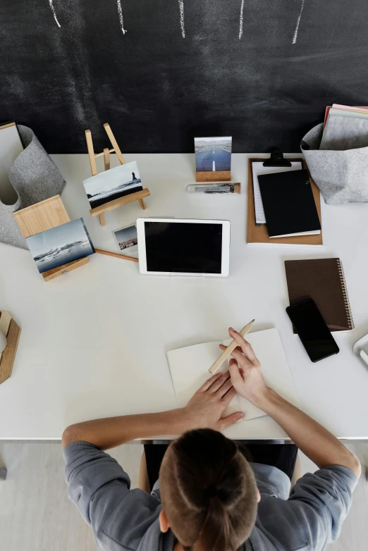 a man sitting at a desk in front of a blackboard, pexels contest winner, sustainable materials, on a white table, collection product, modern office