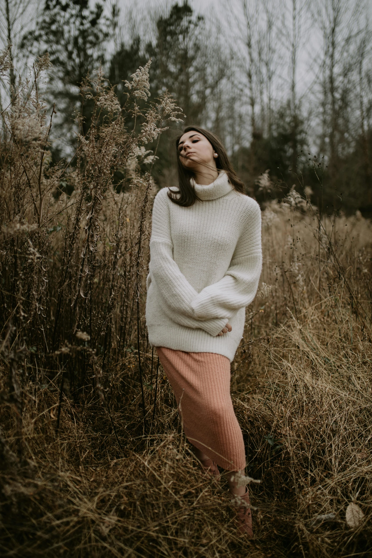 a woman is standing in some long grass