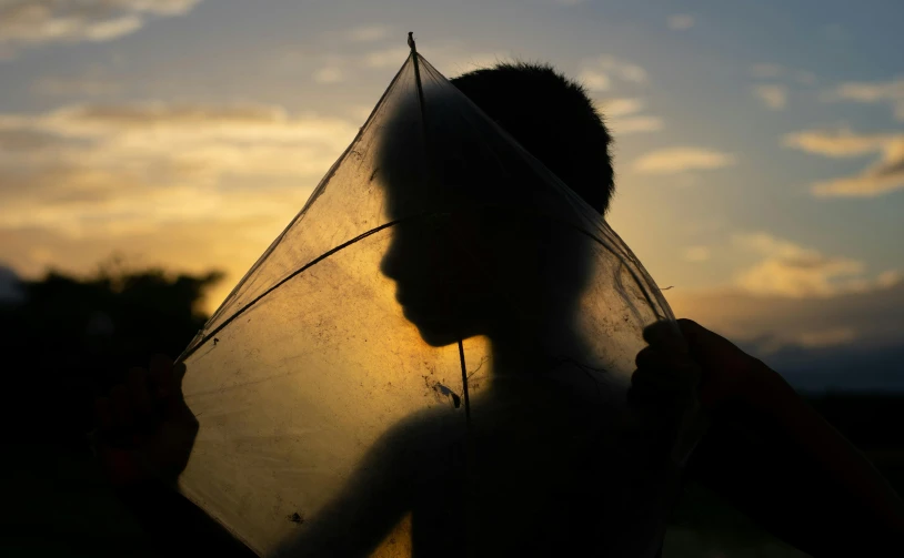 a silhouette of a person holding an umbrella, pexels contest winner, sail made of human skin, boy thin face, ignant, covered head