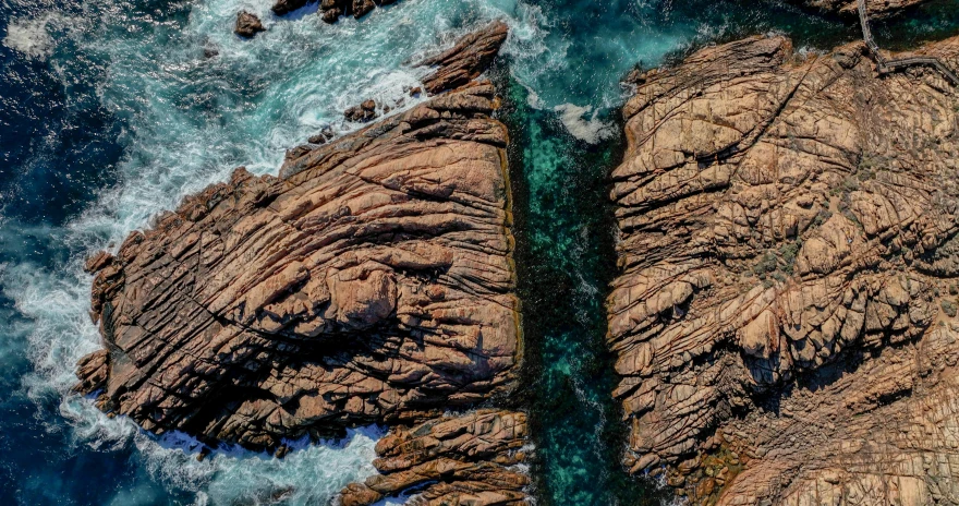 a large body of water next to a rocky shore, pexels contest winner, australia intricate, birdseye view, rock arcs, 8k resolution”