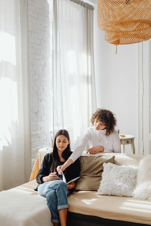 two women sitting on a bed in a room