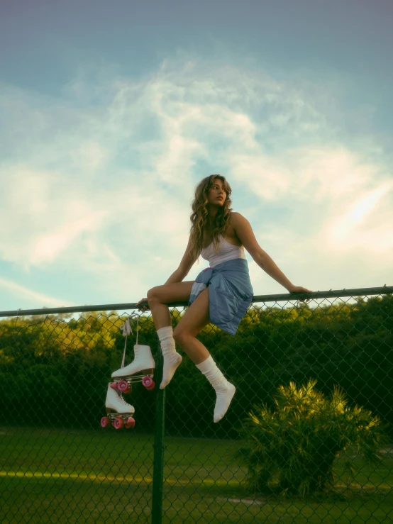 a young woman sitting on top of a green fence