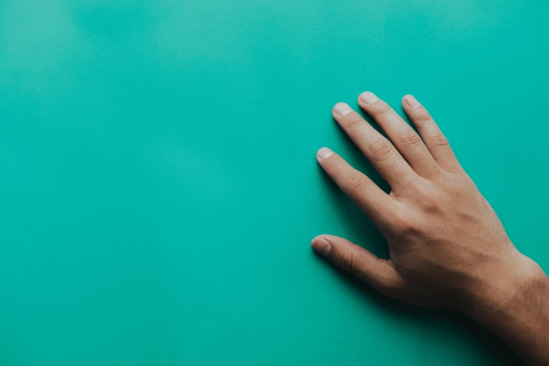 a person's hand on a green surface, trending on unsplash, teal studio backdrop, 15081959 21121991 01012000 4k, incredibly realistic, ignant