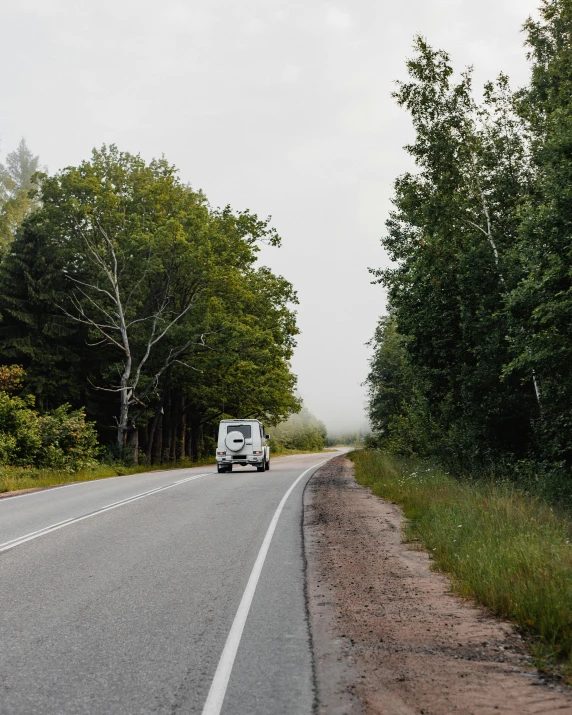 a vehicle on the side of the road with trees in the background