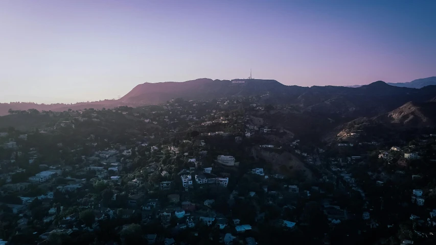 an aerial view of a city with mountains in the background, pexels contest winner, hollywood cinematic, purple sunset, hillside, editorial footage