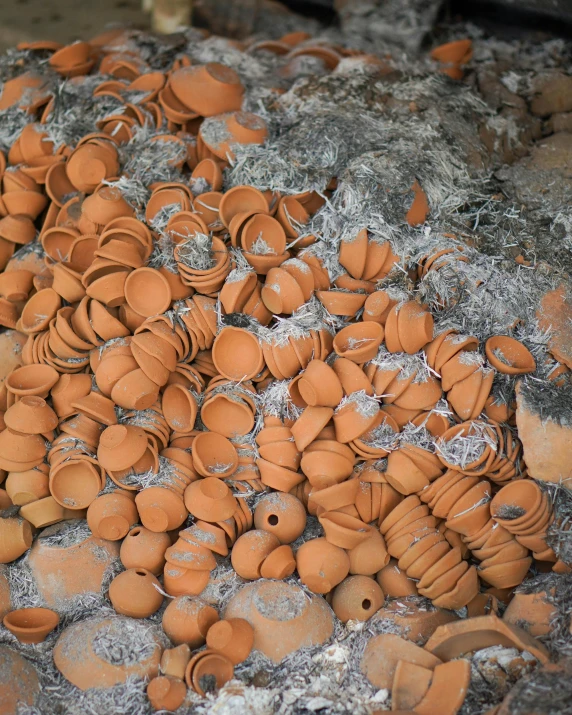 a pile of clay pots sitting on top of a rock, inspired by Andy Goldsworthy, unsplash, confetti, iron smelting pits, orange, poor quality