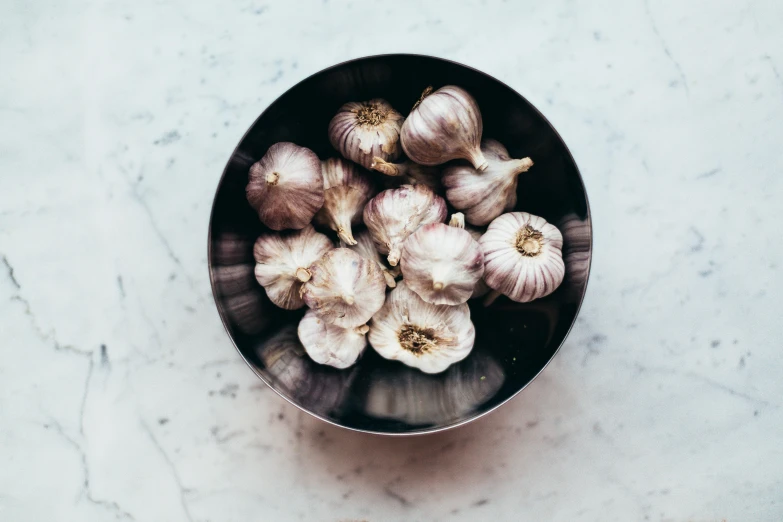 a bowl filled with garlic on top of a table, by Carey Morris, trending on unsplash, stainless steel, grey, multicoloured, all marble