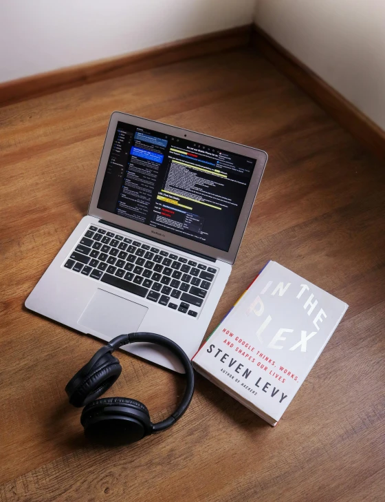 a laptop computer sitting on top of a wooden floor, an album cover, by Adam Rex, pexels, reading engineering book, tony khan wearing a headset, open books, terminal text