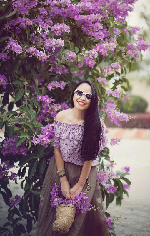 a woman with sunglasses is posing in front of flowers