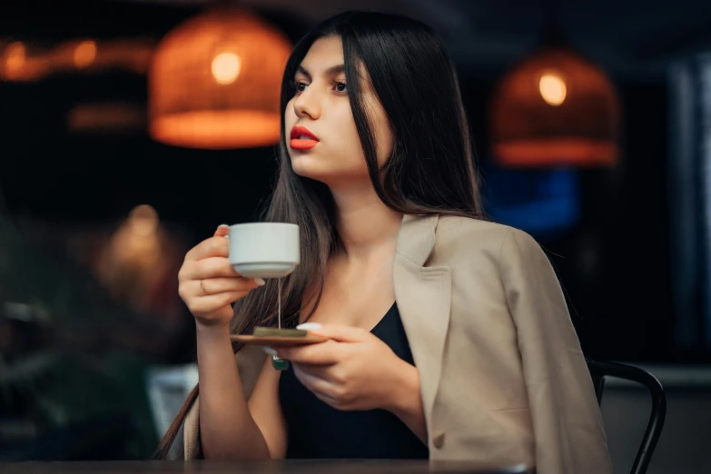 a woman sitting at a table with a cup of coffee, a portrait, trending on pexels, night life, wearing an elegant outfit, girl with dark brown hair, 15081959 21121991 01012000 4k