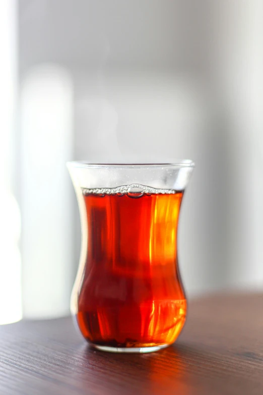 a glass of tea sitting on top of a wooden table, hurufiyya, reds), medium wide front shot, eytan zana, smooth contours