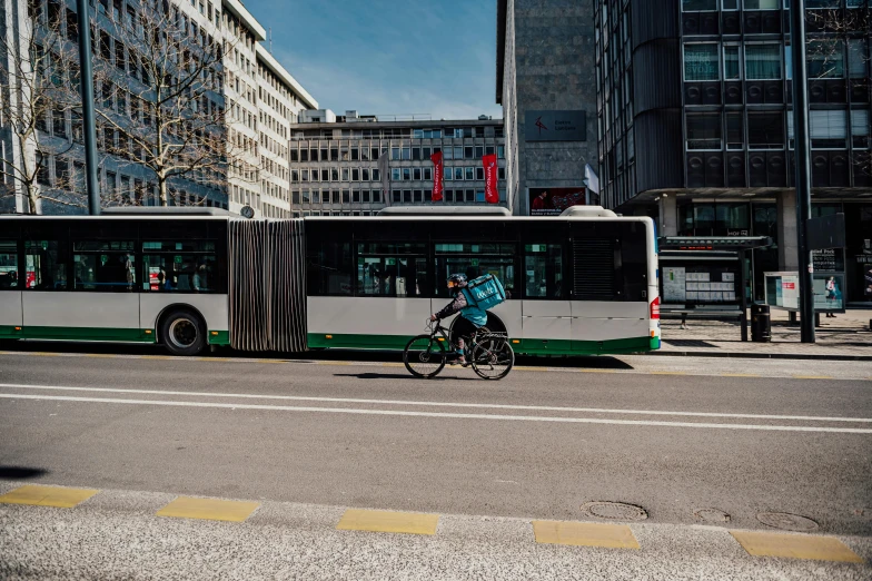 a bicycle rider passes a bus on the street