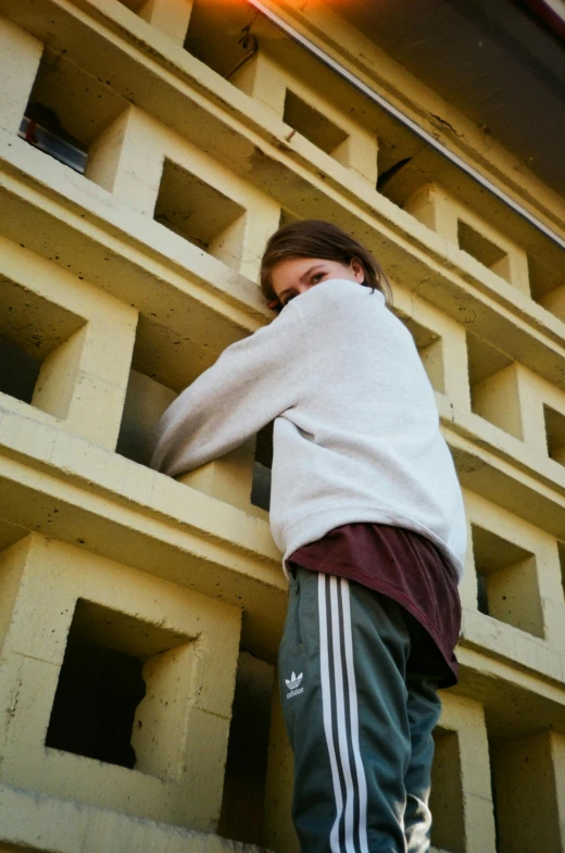 a person on a skateboard in front of a building, an album cover, inspired by Elsa Bleda, unsplash, brutalism, chappie in an adidas track suit, model posing, hiding behind obstacles, teenage girl