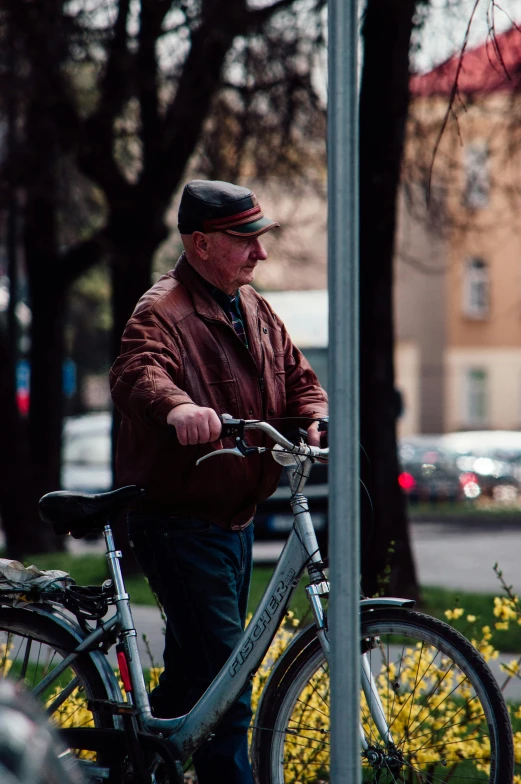 a man standing next to a bicycle on a sidewalk, pexels contest winner, lamp posts, older male, brown, people watching