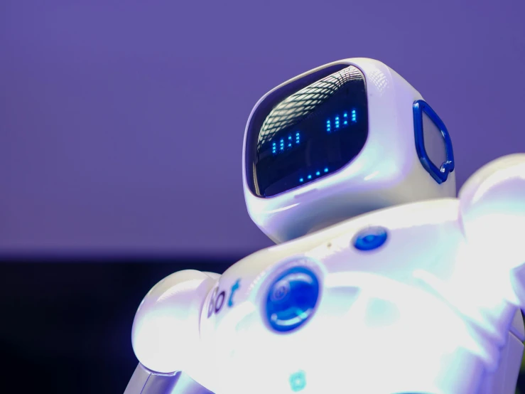 a white robot sitting on top of a table, a hologram, unsplash, purple ambient light, shot on sony a 7, bottom angle, pepper