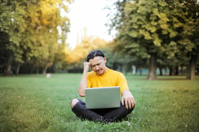 a man sitting in the grass with a laptop, bored ape nft, wearing a modern yellow tshirt, at college, avatar image