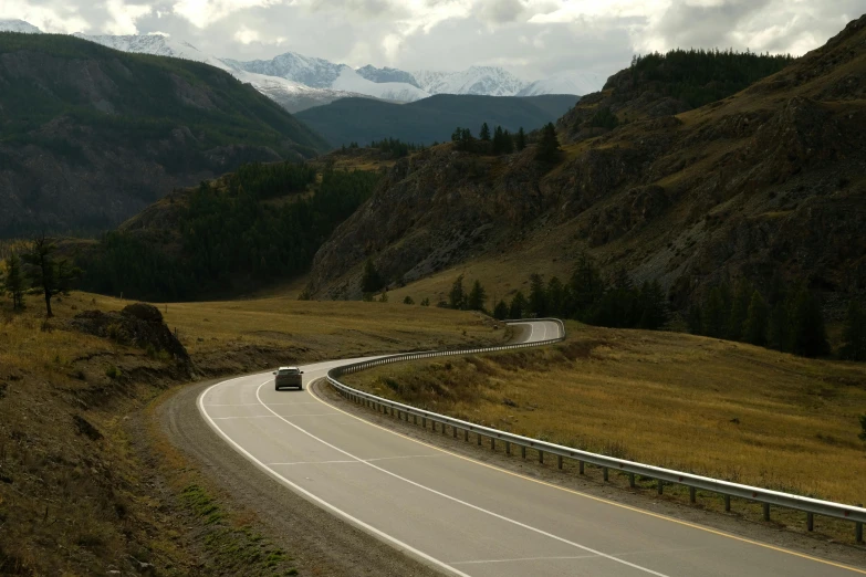 a car driving down a curvy road with mountains in the background, a picture, hurufiyya, bc, fan favorite, mongol, conde nast traveler photo