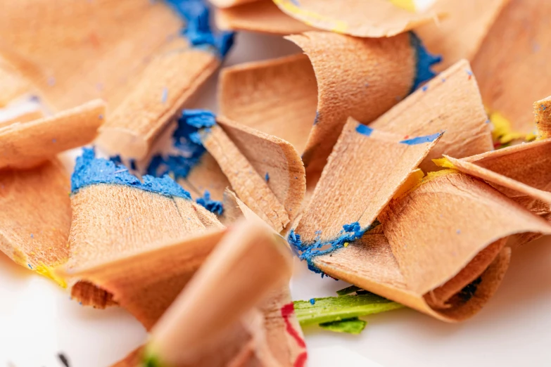 a close up of a bunch of colored pencils, by Nicolette Macnamara, trending on pexels, process art, hand glazed pottery shards, yellow and blue ribbons, closeup at the food, torn paper edges