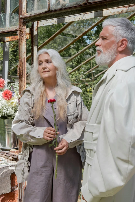 a man standing next to a woman in a greenhouse, an album cover, unsplash, renaissance, long silver hair with a flower, [ theatrical ], midsommar color theme, movie still