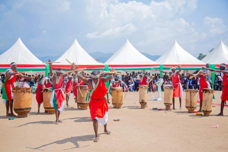 a group of people that are standing in the dirt, hurufiyya, playing drums, masai, on a sunny day, inauguration