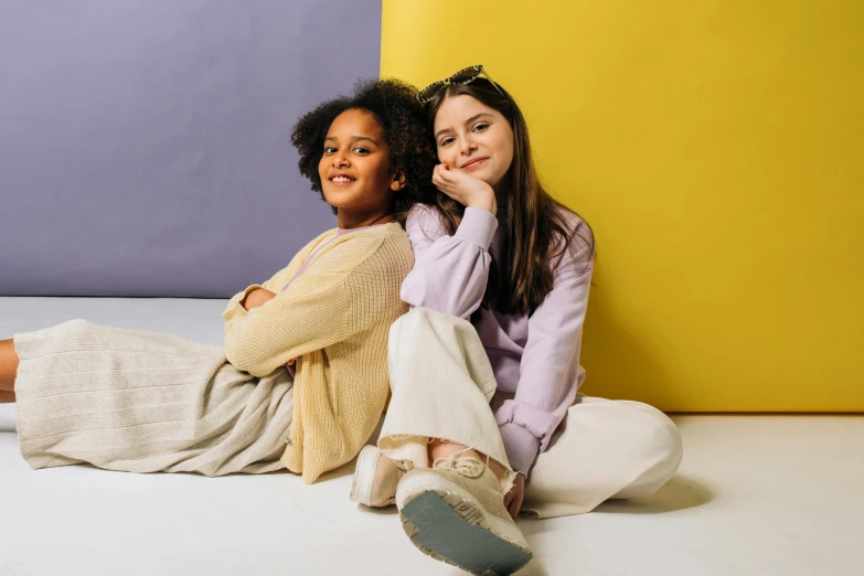 two women sitting next to each other on the floor, trending on pexels, antipodeans, yellow purple, kids, confident pose, neutral colours