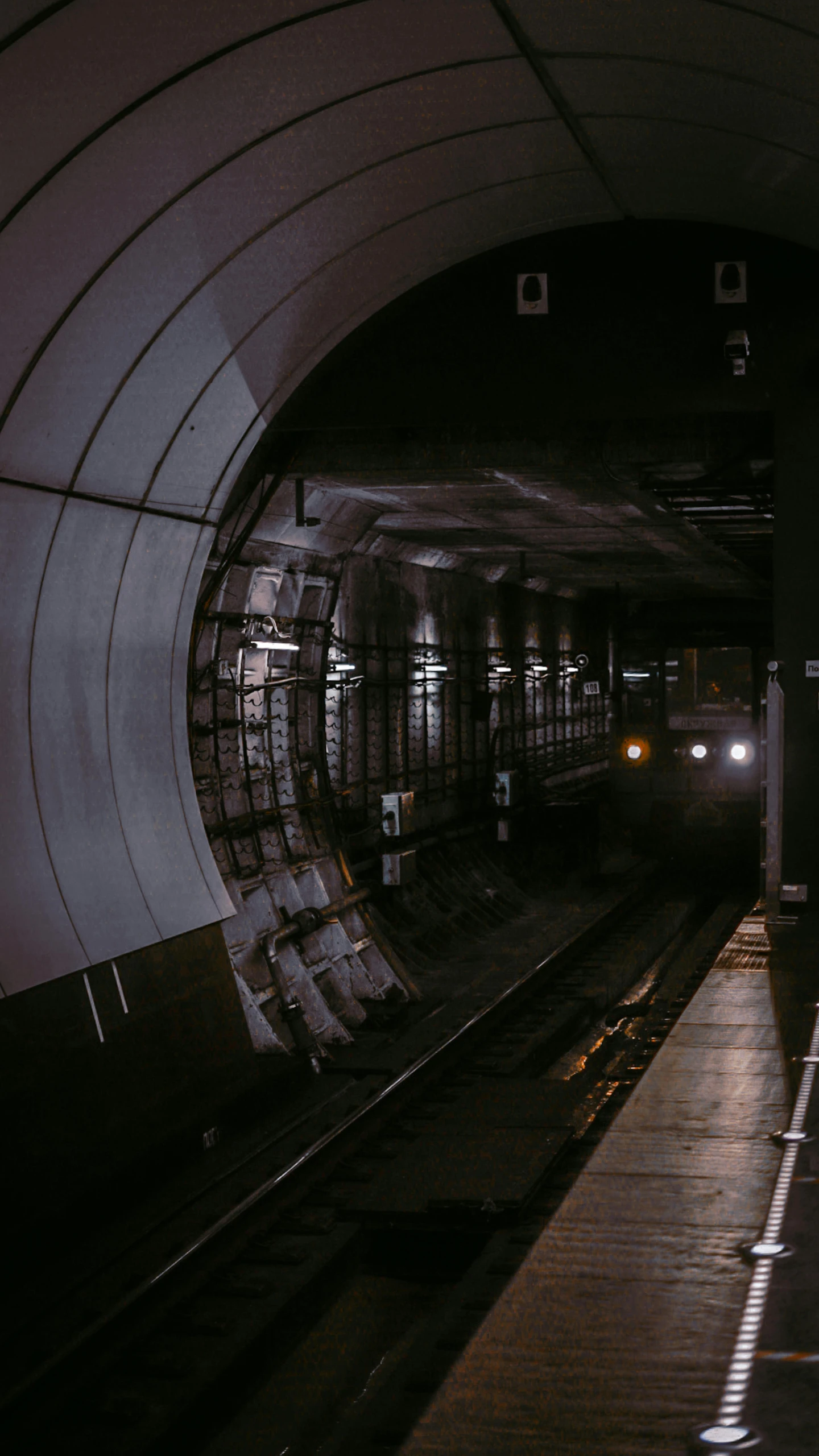 a train traveling through a tunnel next to a platform, inspired by Elsa Bleda, unsplash contest winner, space station, 80s london city, grey, industrial lighting